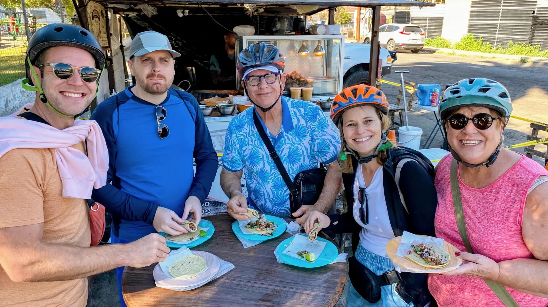 a happy group enjoying Mexican tacos in a bike tour in Ensenada